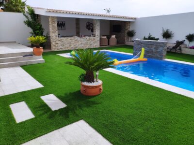 Jardín con piscina y césped artificial